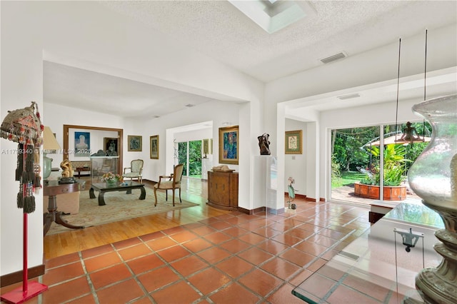 hall featuring a textured ceiling, baseboards, and tile patterned flooring