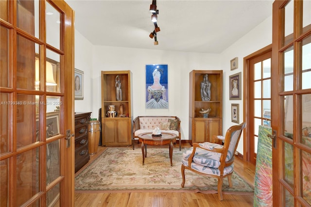 sitting room with french doors, track lighting, and wood finished floors