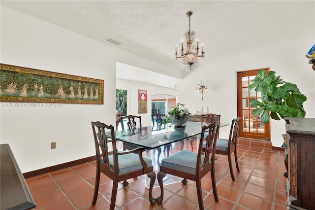 tiled dining space featuring a chandelier, a textured ceiling, and baseboards