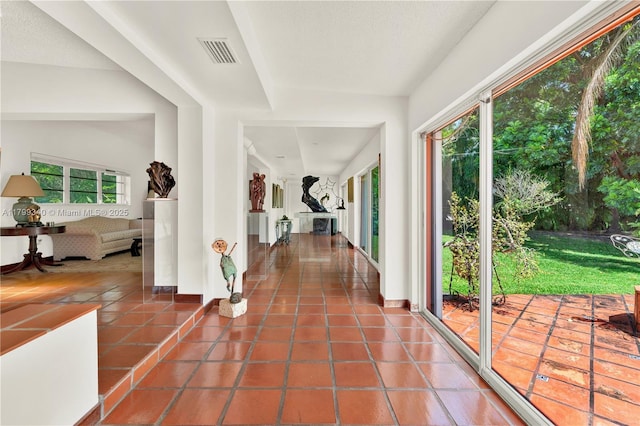 hallway featuring plenty of natural light, tile patterned floors, and baseboards