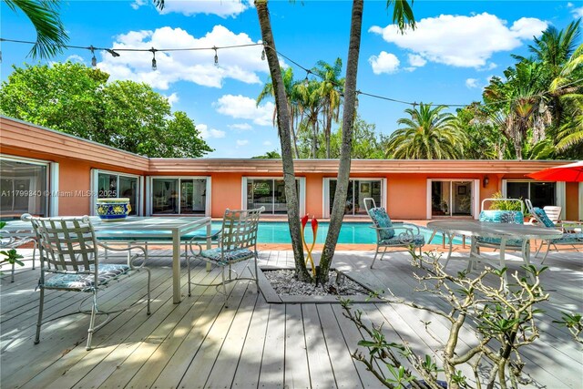 outdoor pool with a wooden deck and outdoor dining space