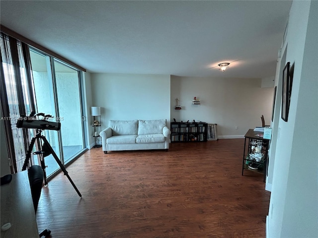 living area featuring healthy amount of natural light, dark wood finished floors, baseboards, and expansive windows