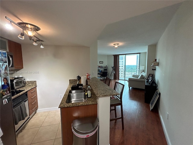 kitchen with a sink, wall oven, a peninsula, a kitchen breakfast bar, and stainless steel microwave