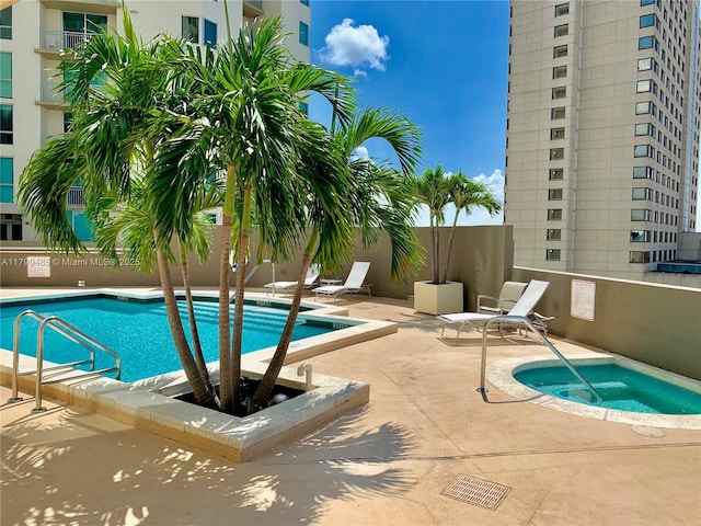 community pool featuring a hot tub and a patio area