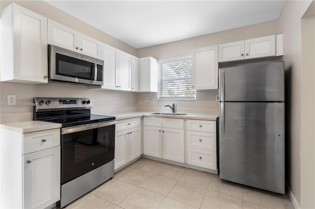 kitchen with stainless steel appliances, a sink, light countertops, white cabinets, and light tile patterned floors