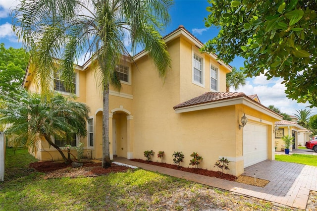 mediterranean / spanish-style house with stucco siding, a tiled roof, and driveway