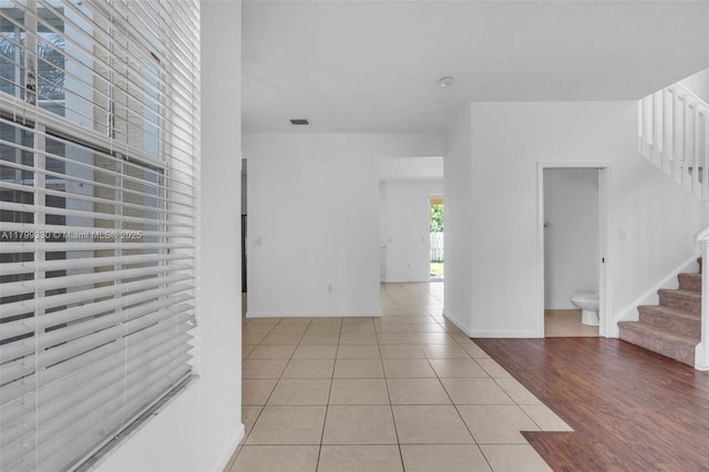 unfurnished room featuring stairs, tile patterned floors, and baseboards