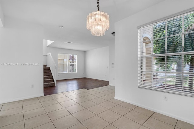 empty room with tile patterned floors, stairway, a chandelier, and baseboards