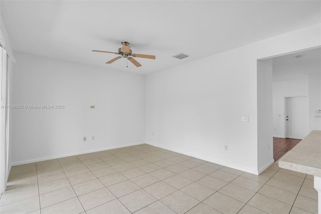 spare room with a ceiling fan, light tile patterned floors, and baseboards
