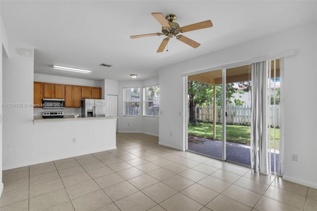 kitchen featuring appliances with stainless steel finishes, a peninsula, ceiling fan, brown cabinetry, and baseboards