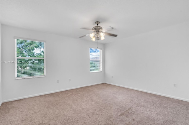 carpeted spare room featuring ceiling fan and baseboards