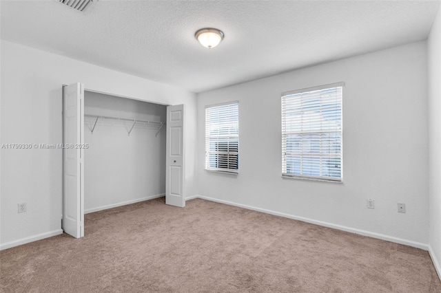 unfurnished bedroom with carpet, a closet, baseboards, and a textured ceiling