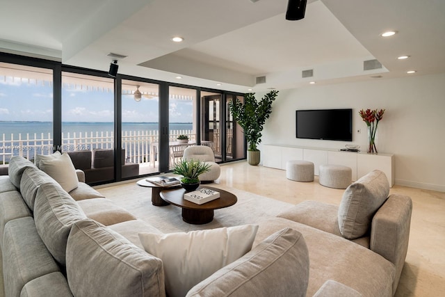 living room with a wall of windows, a tray ceiling, recessed lighting, and baseboards