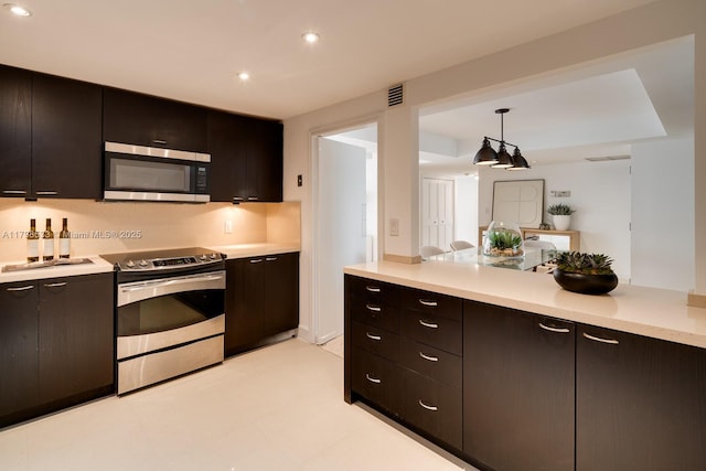 kitchen with stainless steel appliances, light countertops, decorative light fixtures, recessed lighting, and open floor plan