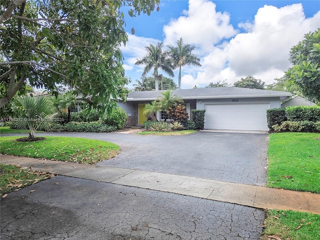 view of front of home with asphalt driveway, an attached garage, a front lawn, and stucco siding