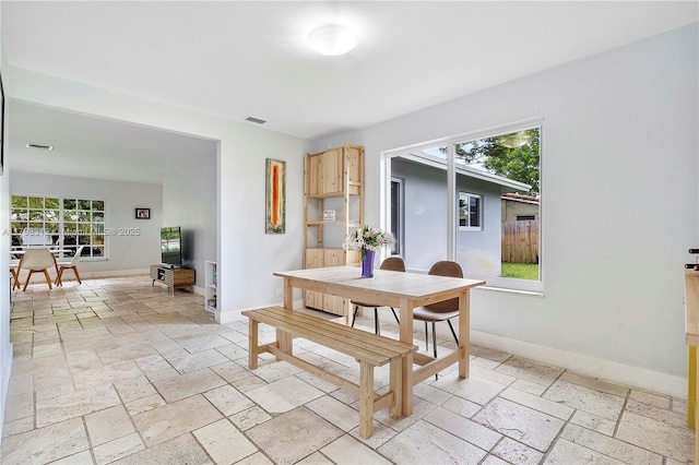 dining room with stone tile flooring and baseboards