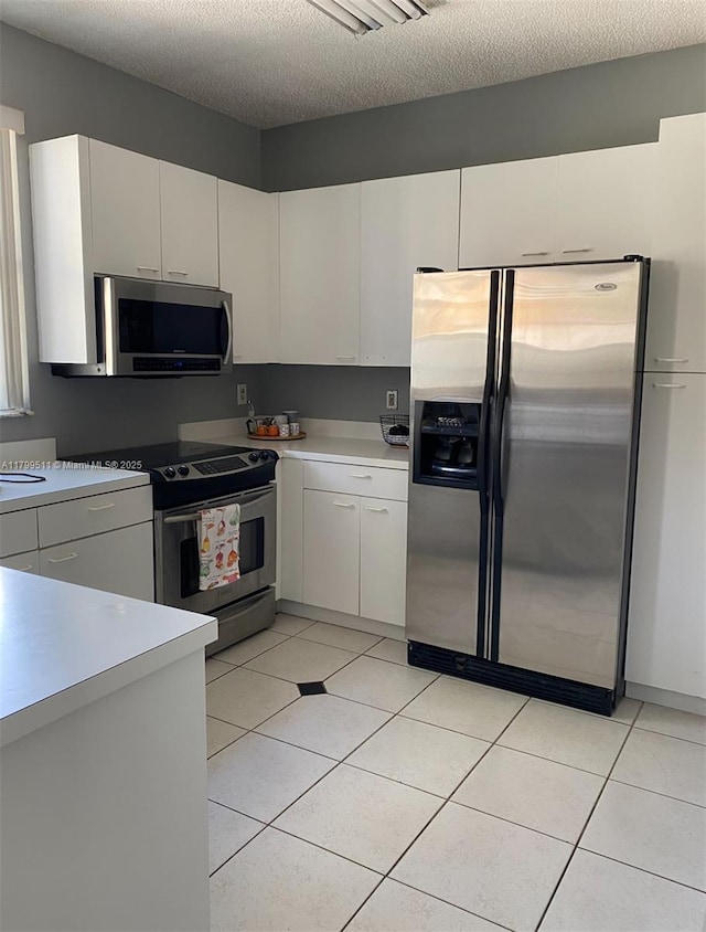 15456 NW 12th Pl, Pembroke Pines, FL 33028 - kitchen with stainless steel appliances, light countertops, light tile patterned flooring, white cabinetry, and a textured ceiling