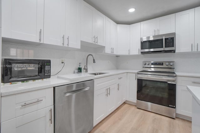 216 San Remo Blvd, North Lauderdale, FL 33068 - kitchen with appliances with stainless steel finishes, white cabinets, light wood-type flooring, a sink, and recessed lighting