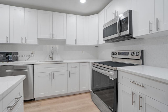 216 San Remo Blvd, North Lauderdale, FL 33068 - kitchen with stainless steel appliances, a sink, white cabinets, light wood-type flooring, and recessed lighting