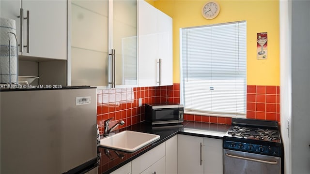 1051 Euclid Ave Unit 208, Miami Beach, FL 33139 - kitchen featuring appliances with stainless steel finishes, a sink, white cabinetry, backsplash, and dark countertops
