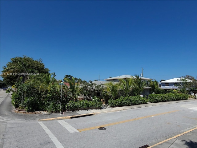 view of asphalt road featuring curbs, street lights, and sidewalks