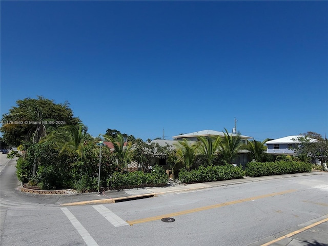 view of asphalt road with curbs and sidewalks