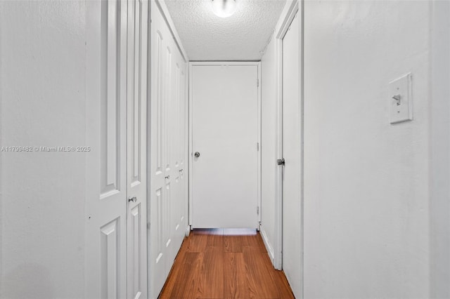 251 174th St Unit 212, Sunny Isles Beach, FL 33160 - hallway featuring a textured ceiling and wood finished floors