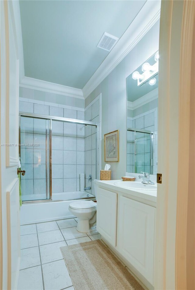 bathroom featuring crown molding, tile patterned floors, toilet, vanity, and enclosed tub / shower combo