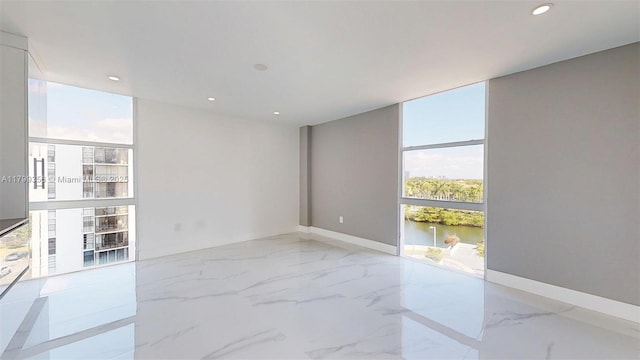 3625 N Country Club Dr Unit 609, Aventura, FL 33180 - spare room featuring a wall of windows, marble tiled flooring, recessed lighting, a water view, and baseboards