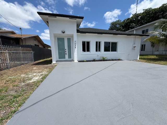 3039 NW 51st Ter, Miami, FL 33142 - view of front of home featuring stucco siding, fence, a patio, and french doors
