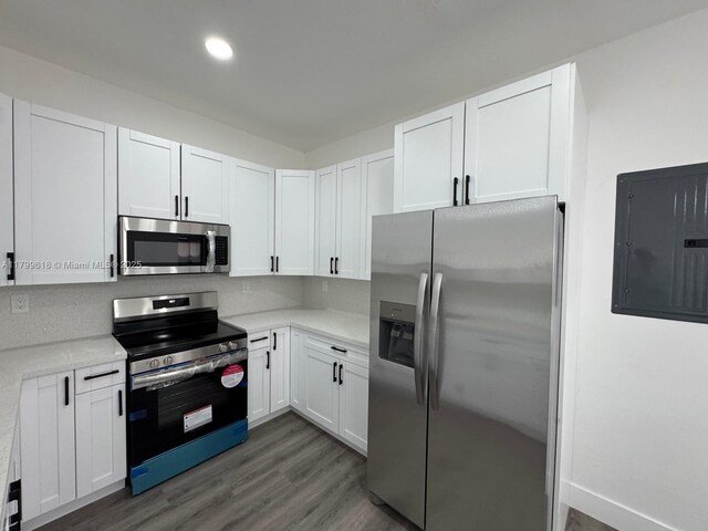 3039 NW 51st Ter, Miami, FL 33142 - kitchen with stainless steel appliances, electric panel, light countertops, dark wood finished floors, and white cabinetry
