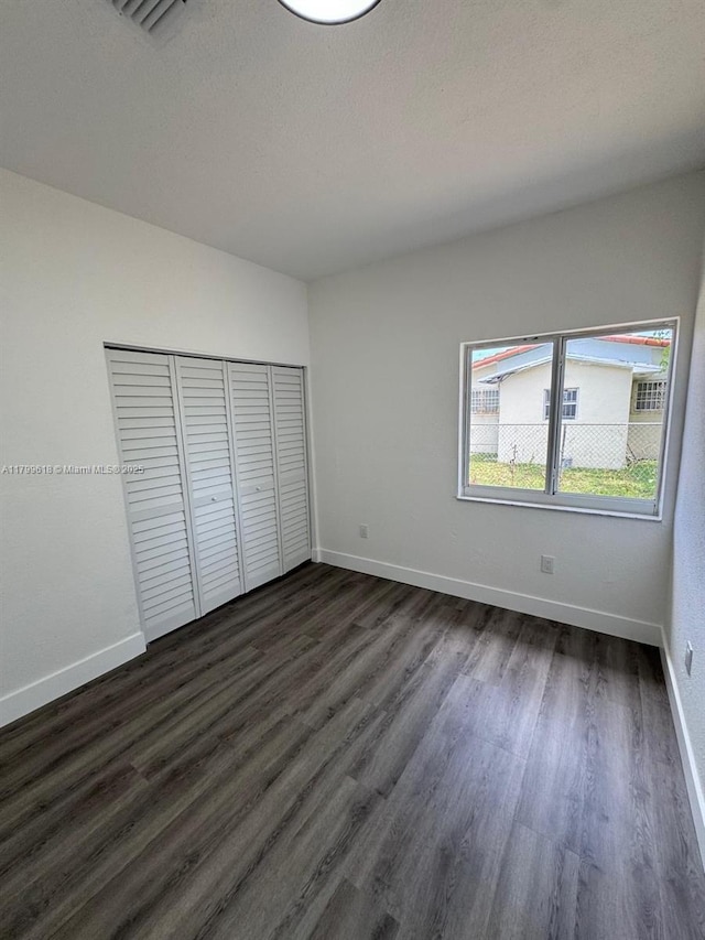 3039 NW 51st Ter, Miami, FL 33142 - unfurnished bedroom featuring dark wood-type flooring, baseboards, and a closet