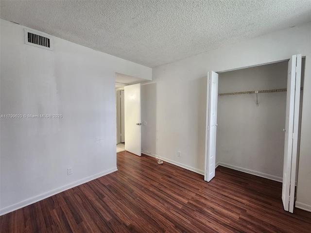 216 Lake Pointe Dr Unit 128, Oakland Park, FL 33309 - unfurnished bedroom with dark wood-style floors, a closet, baseboards, and a textured ceiling