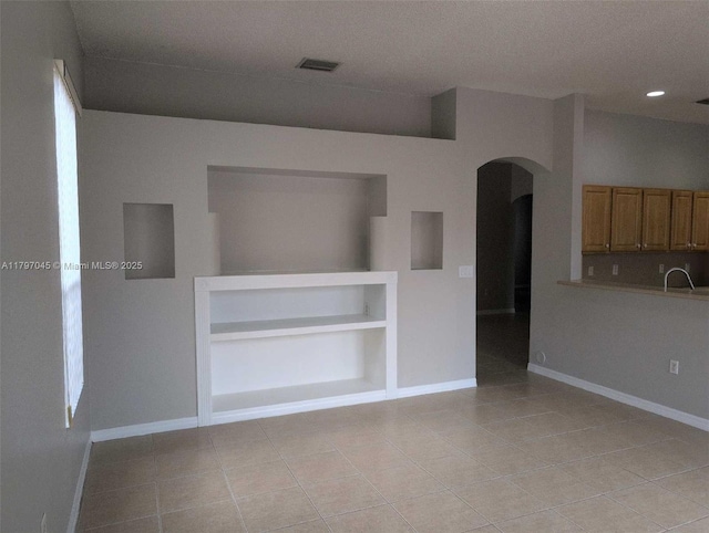 2013 NE 3rd Ct, Homestead, FL 33033 - empty room featuring arched walkways, light tile patterned flooring, baseboards, recessed lighting, and a sink