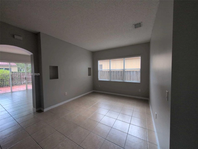2013 NE 3rd Ct, Homestead, FL 33033 - empty room featuring plenty of natural light, arched walkways, tile patterned flooring, a textured ceiling, and baseboards