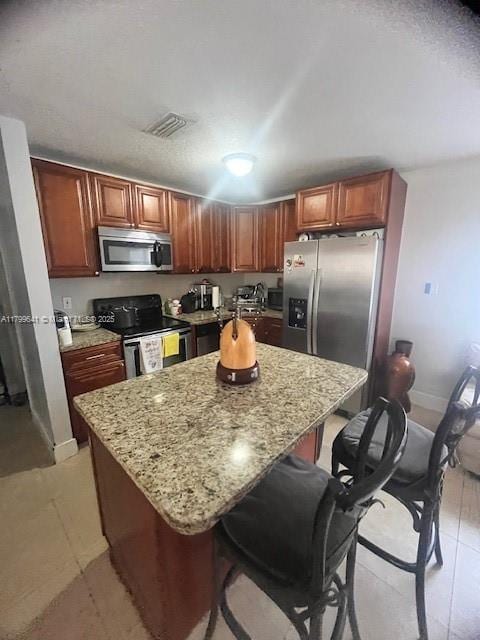 717 NW 1st St, Hallandale Beach, FL 33009 - kitchen with stainless steel appliances, a breakfast bar area, light stone counters, a center island, and light tile patterned floors