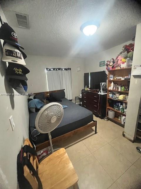 717 NW 1st St, Hallandale Beach, FL 33009 - bedroom featuring light tile patterned floors and a textured ceiling