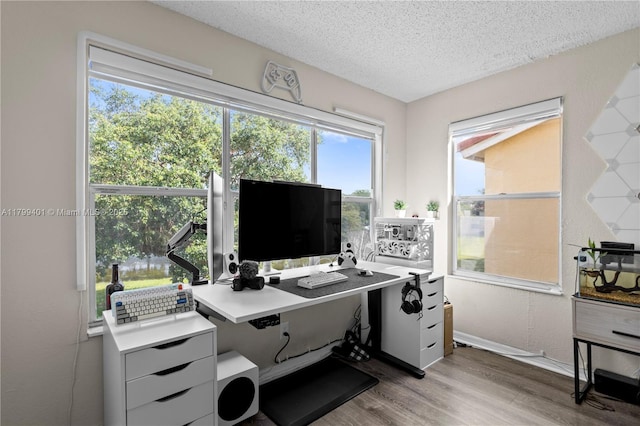 office area with light wood finished floors, a textured ceiling, and baseboards