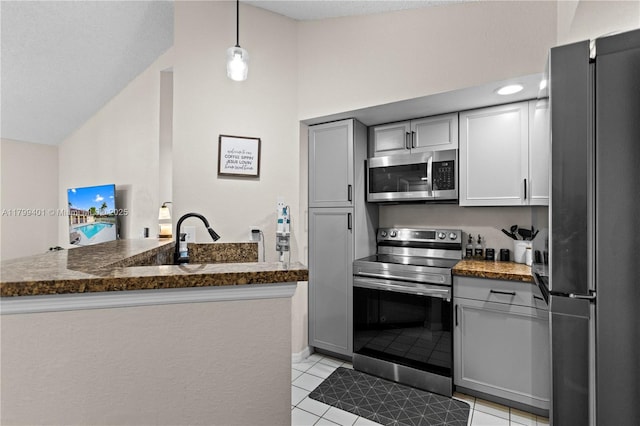 kitchen featuring stainless steel appliances, vaulted ceiling, light tile patterned floors, gray cabinets, and hanging light fixtures