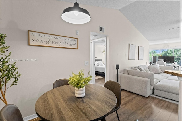 dining area featuring vaulted ceiling and wood finished floors
