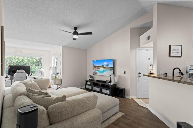 bedroom featuring lofted ceiling, wood finished floors, baseboards, ceiling fan, and a textured ceiling