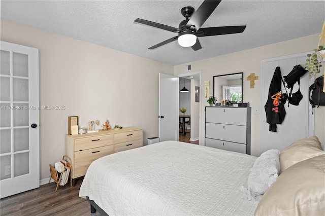 bedroom with dark wood-style floors, a closet, a textured ceiling, a ceiling fan, and baseboards