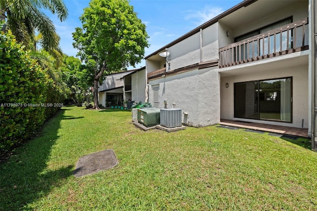 view of grassy yard featuring cooling unit and a balcony