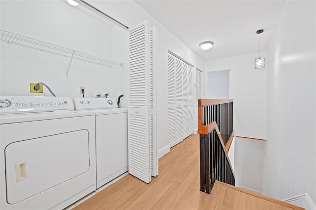 laundry room featuring washer and dryer, light wood finished floors, and baseboards