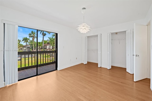 unfurnished bedroom featuring access to exterior, multiple closets, light wood-style floors, and baseboards