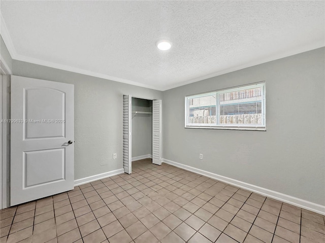 unfurnished bedroom with a textured ceiling, a closet, baseboards, and ornamental molding