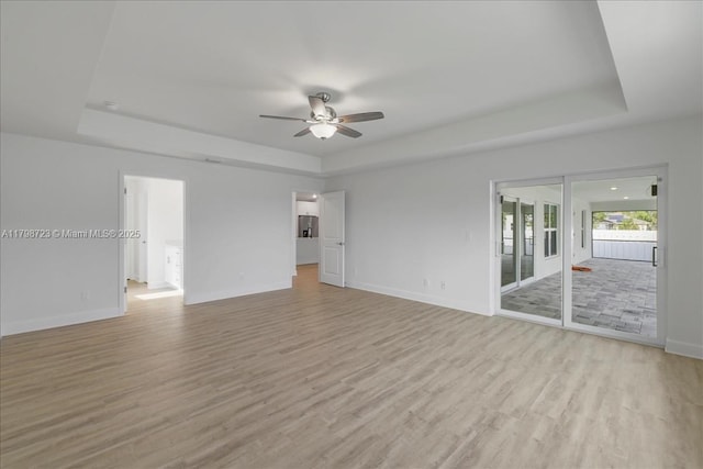2048 NW 3rd Ter, Cape Coral, FL 33993 - unfurnished living room featuring a tray ceiling, a ceiling fan, and light wood-type flooring