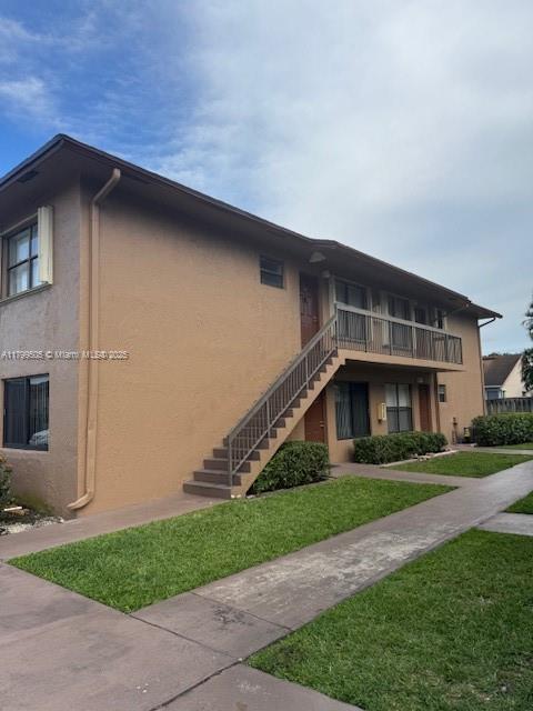 10047 Winding Lake Rd Unit 203, Sunrise, FL 33351 - view of home's exterior with stairs, stucco siding, and a yard