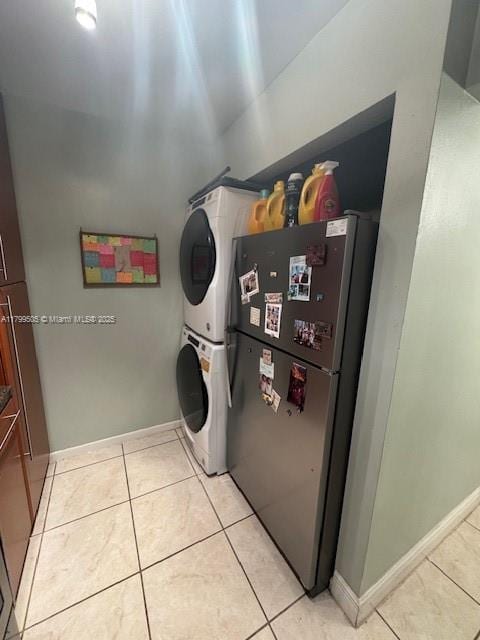 10047 Winding Lake Rd Unit 203, Sunrise, FL 33351 - clothes washing area featuring stacked washer and clothes dryer, light tile patterned floors, and baseboards