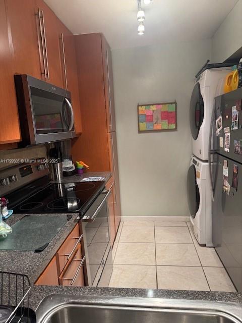 10047 Winding Lake Rd Unit 203, Sunrise, FL 33351 - kitchen with appliances with stainless steel finishes, estacked washer and dryer, brown cabinetry, and tile patterned floors